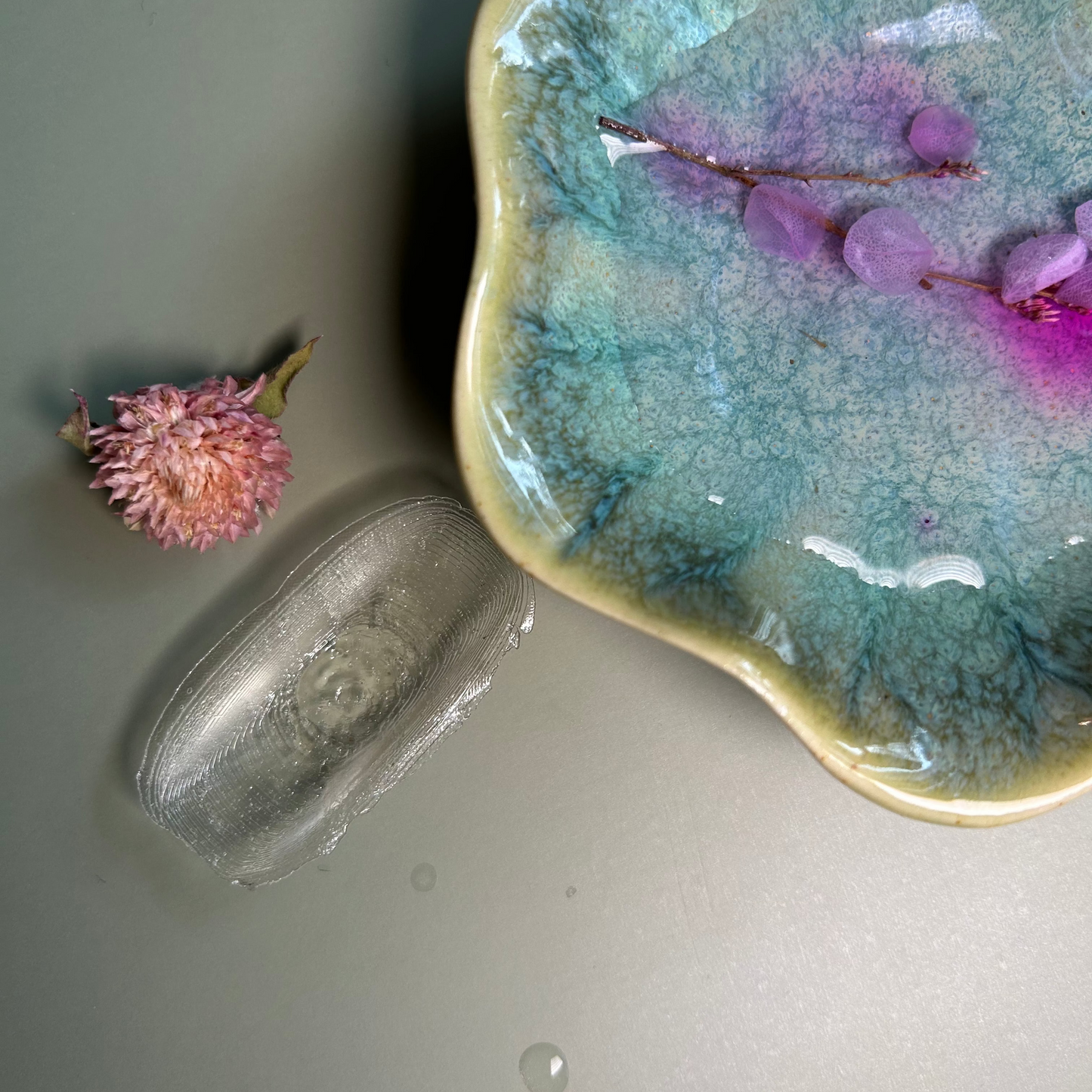 A ceramic heel protection accessory with a leaf shape, displayed on a flat surface alongside a small, round object which appears to be a marble.